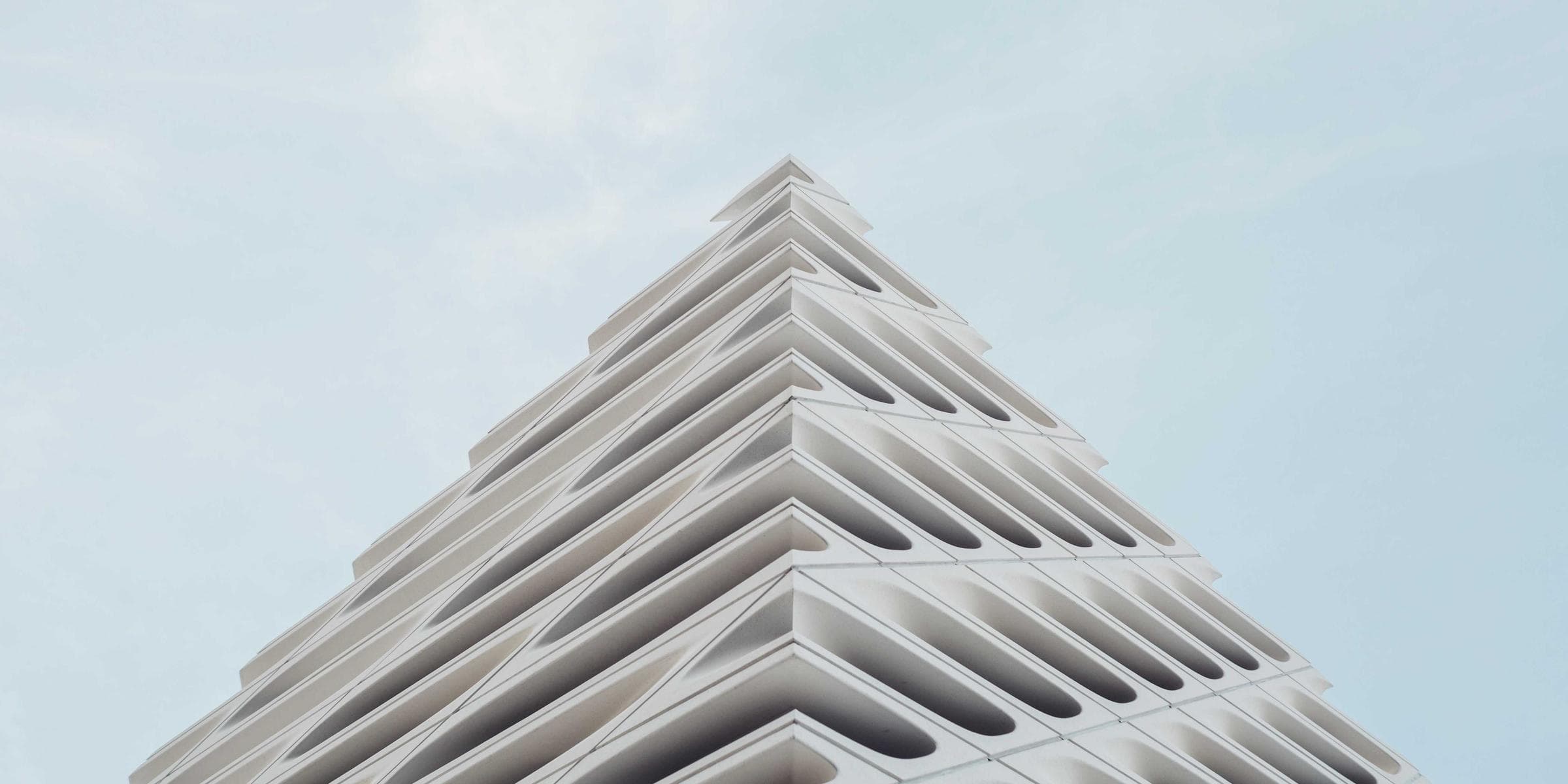 Stepped white modern building corner against a pale sky - photo by Julien Moreau