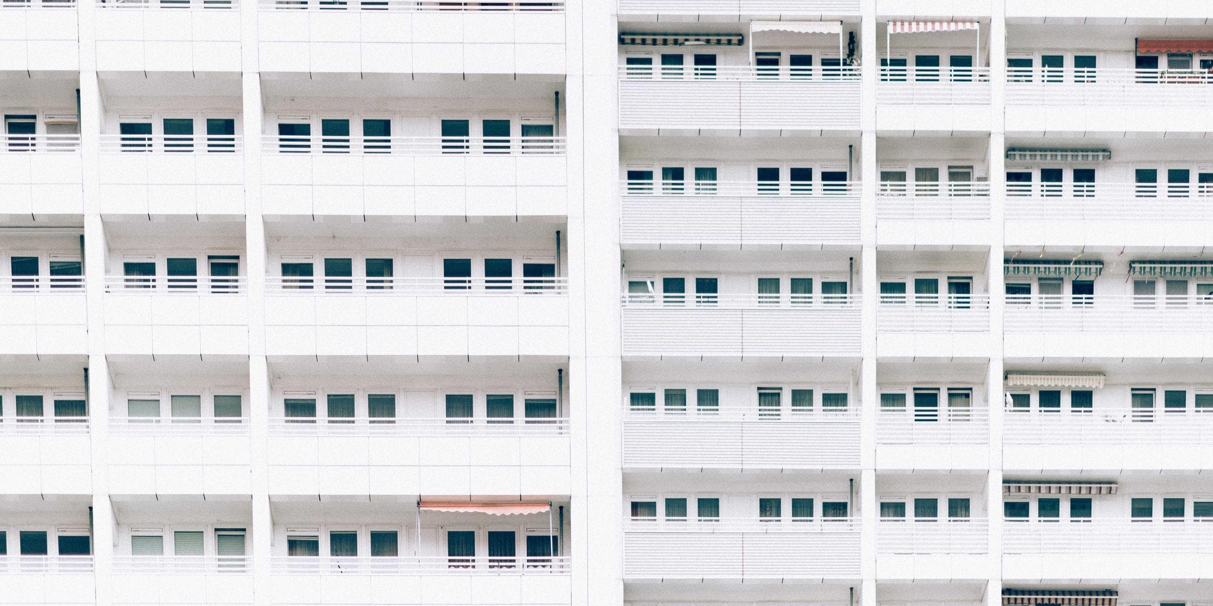 White apartment facade with repeating balconies - photo by Roman Kraft